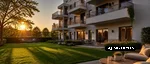 Mehrfamilienhaus mit gepflegten Rasenflächen und grüner Außenanlage bei Sonnenuntergang.